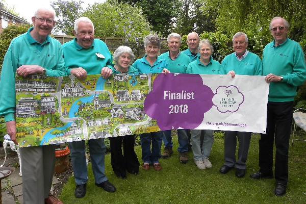 Members of the Wimborne in Bloom Committee displaying the RHS Britain in Bloom banner at the coffee morning